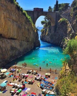 A coastal scene with a clear blue sea, a rocky cliff, and a bridge. - Fico d'India Relais (Furore)