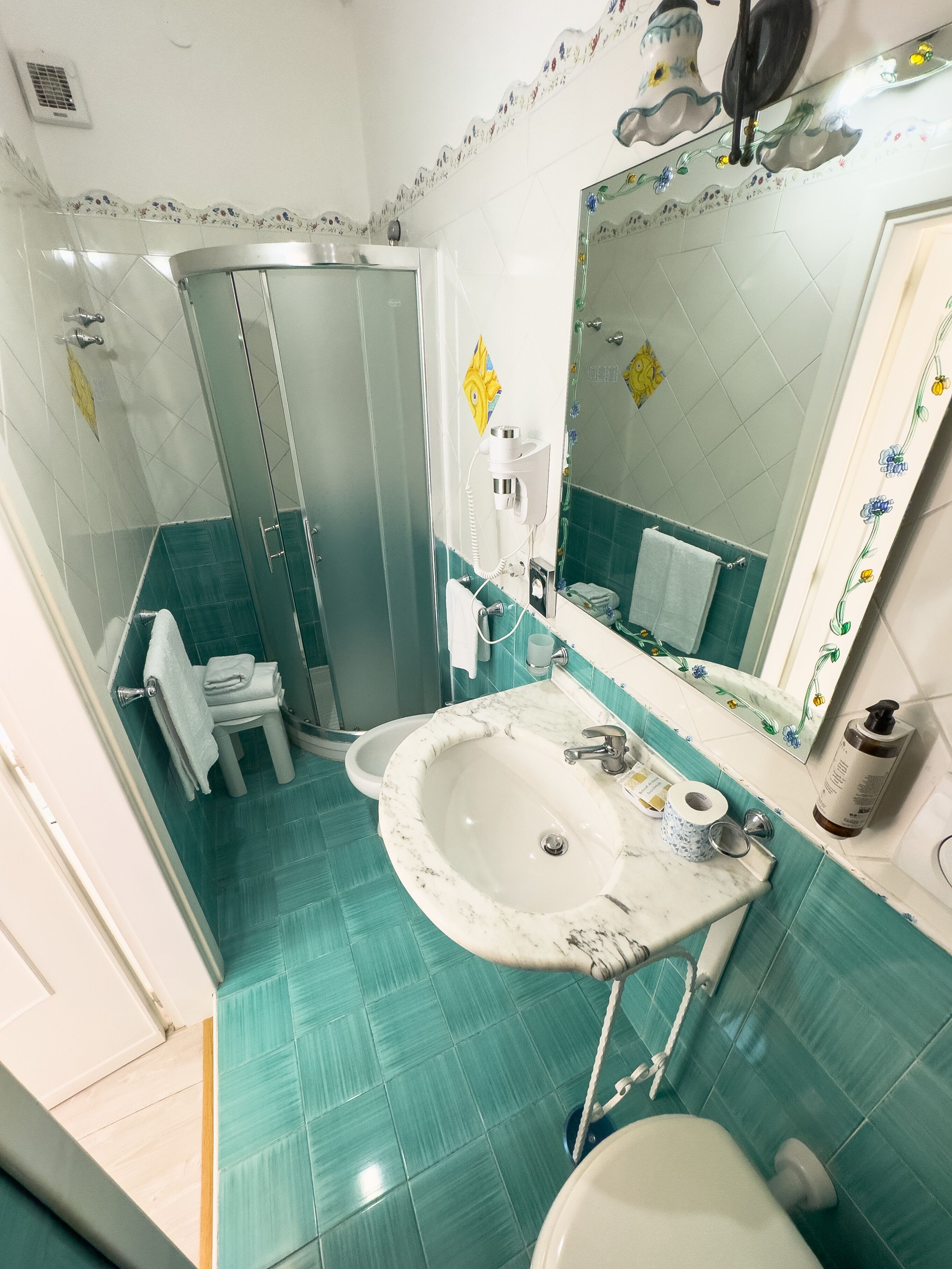 Une salle de bain équipée d’un lavabo, d’un miroir, d’une douche et de toilettes.