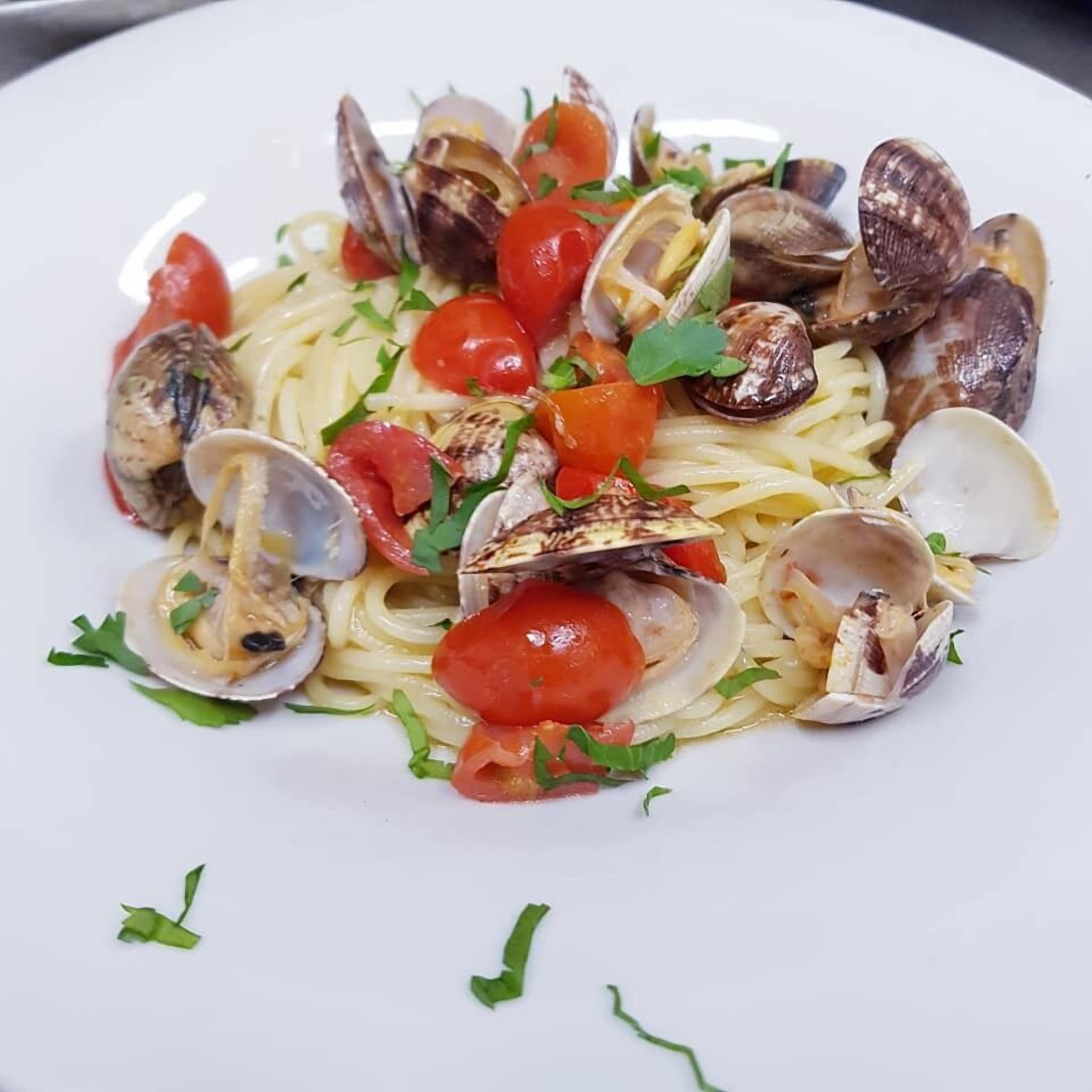 A plate of spaghetti with clams and cherry tomatoes.