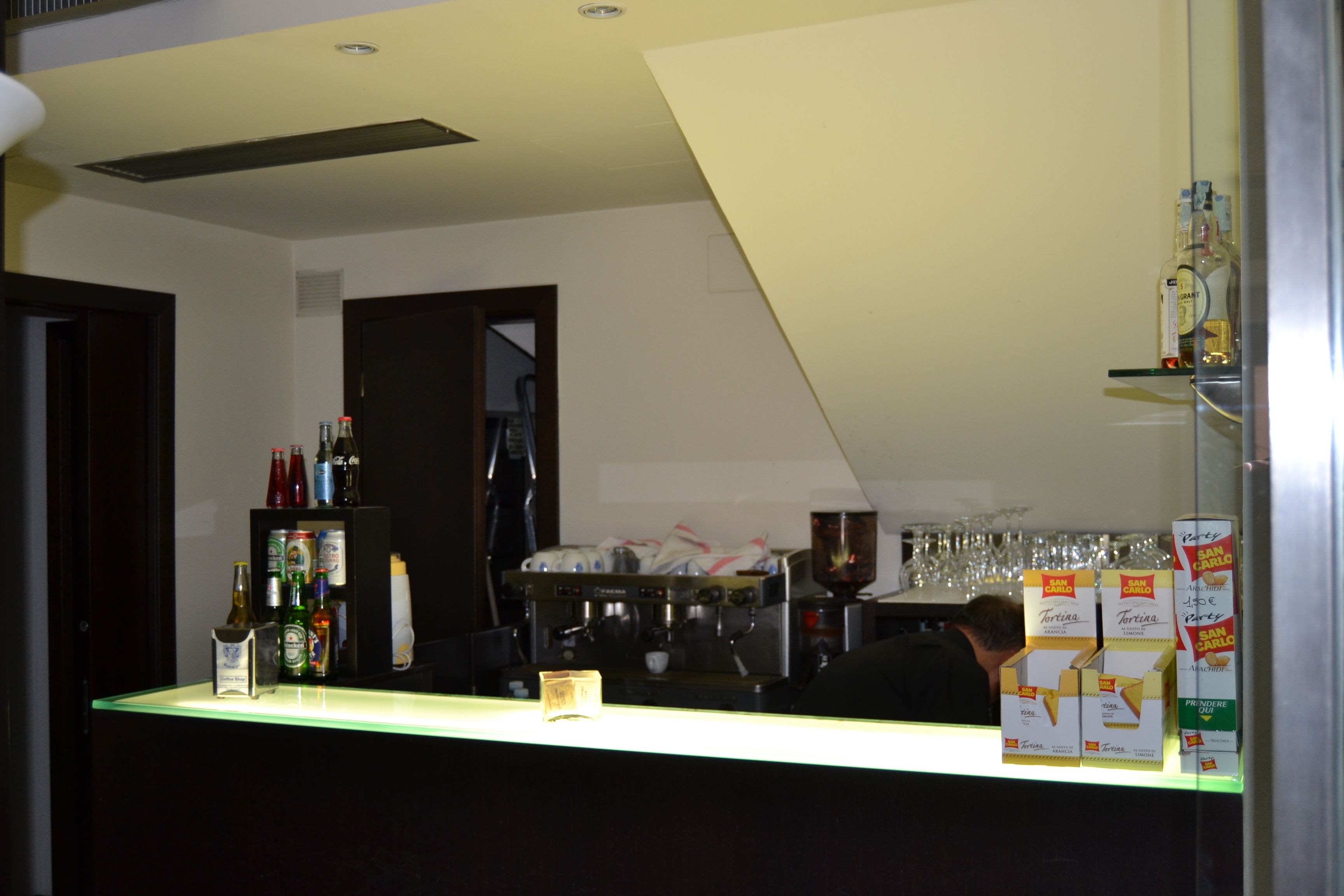 A bar area with a counter, shelves of bottles, and glasses.