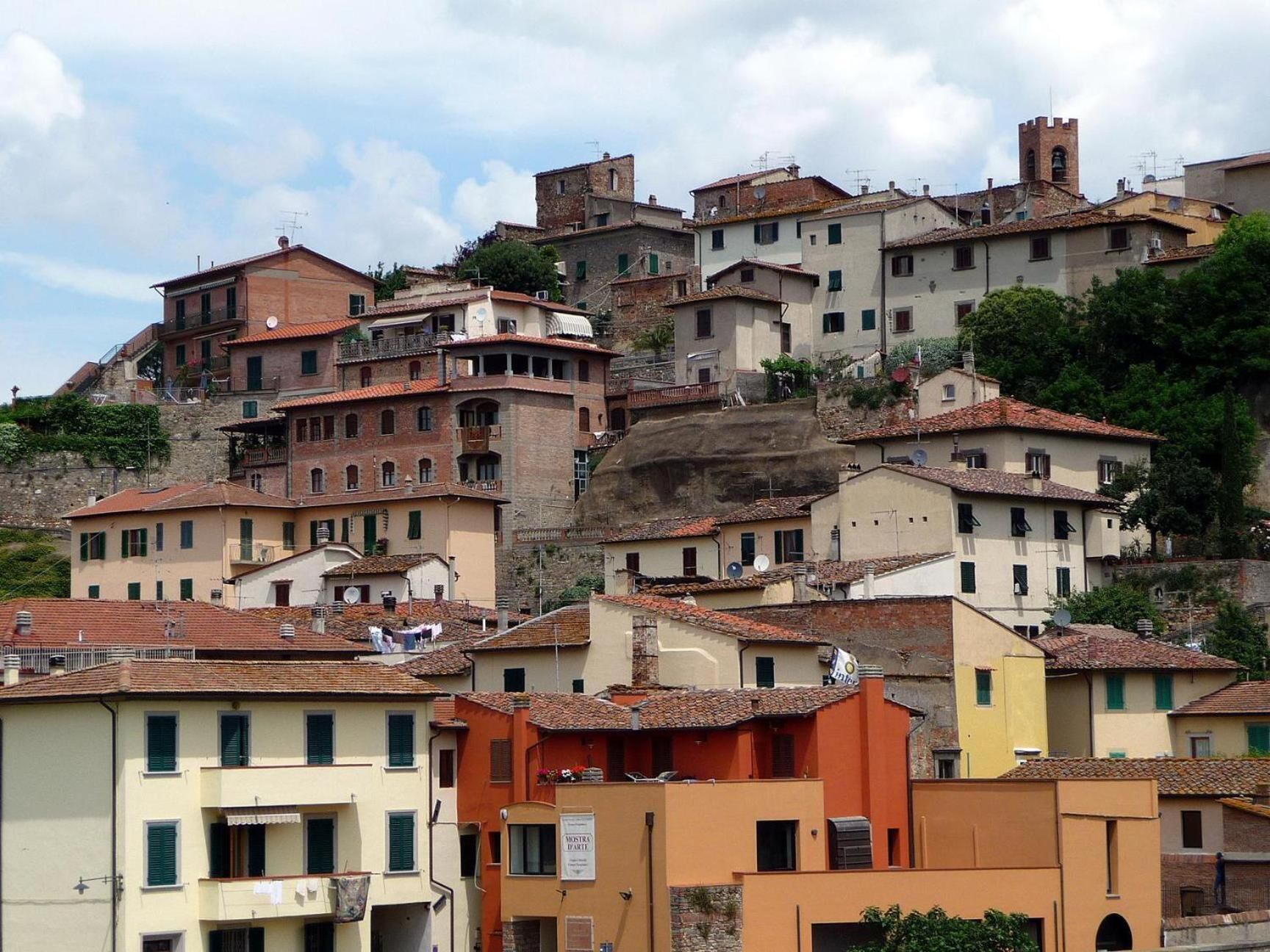 A hillside of traditional buildings with terracotta roofs, some with balconies and signage indicating local businesses.