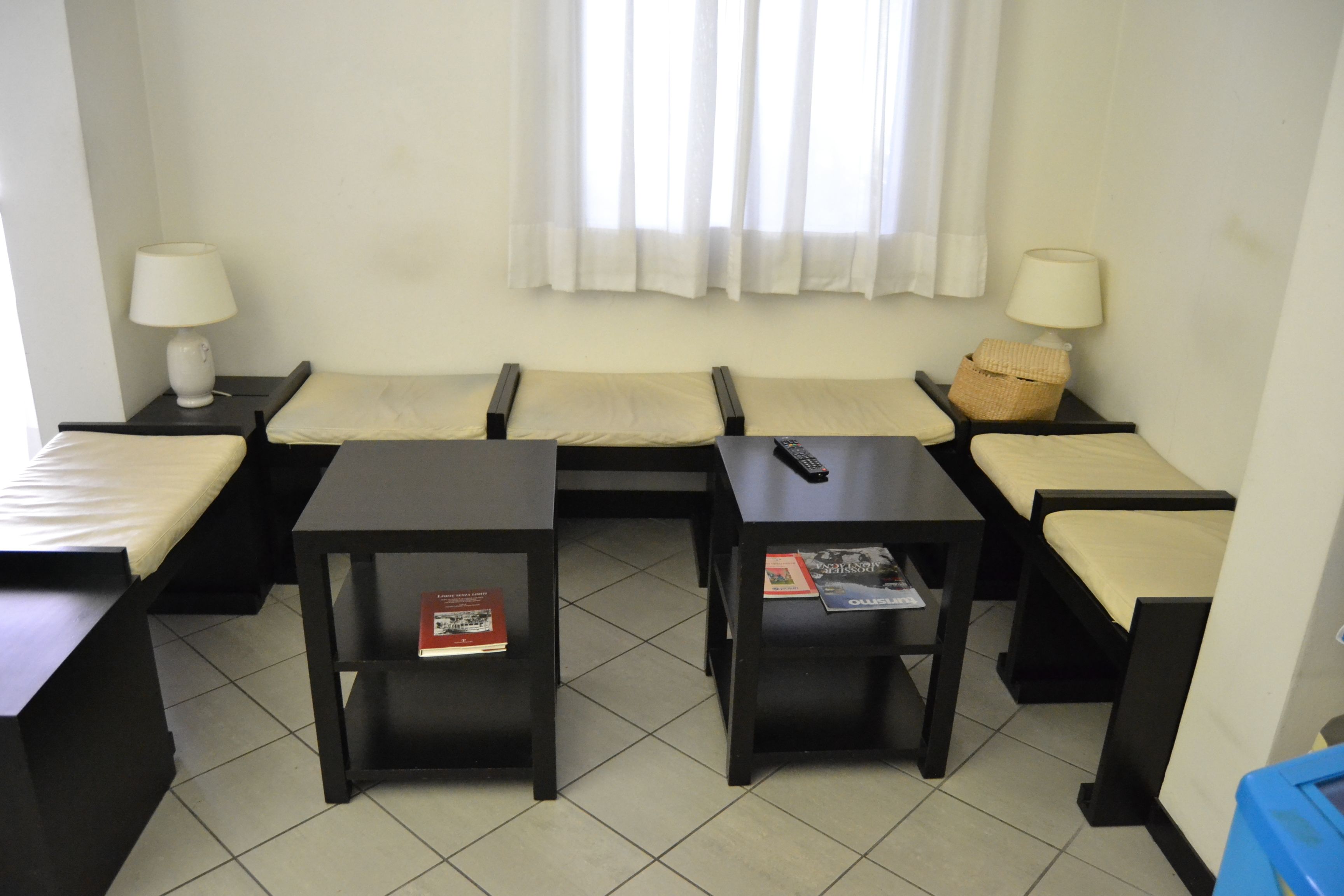 Una habitación con dos camas individuales, dos mesitas y una ventana con cortinas.
