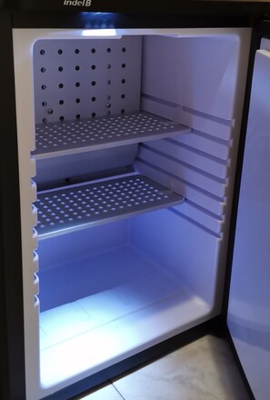 Avoin jääkaappi, jossa on kolme hyllyä ja pakastelokero.