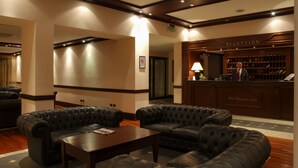A lobby with leather sofas, a reception desk, and a wooden floor.