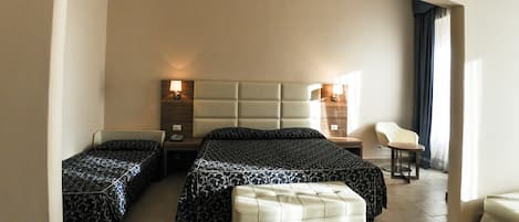 A hotel room with two beds, a sitting area, and a small table.
