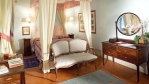 Ein Schlafzimmer mit Baldachinbett, Nachttischlampen, Kommode und Spiegel.