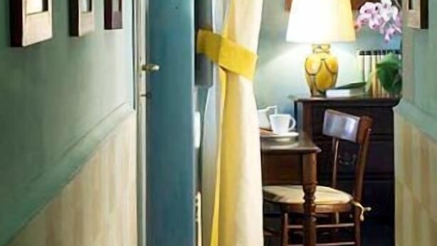 Ein Zimmer mit einer bogenförmigen Tür, die in einen Essbereich führt. Es gibt einen Tisch mit Stühlen, eine Lampe und eine Vase mit Blumen.