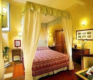 A room with a four-poster bed, a wooden wardrobe, a nightstand, and a wall-mounted lamp. - Antica Dimora Firenze  (Florence)
