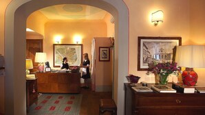 Eine Hotelhalle mit einer Rezeption, einer Karte, einem gerahmten Bild und einem Blumenstrauß.