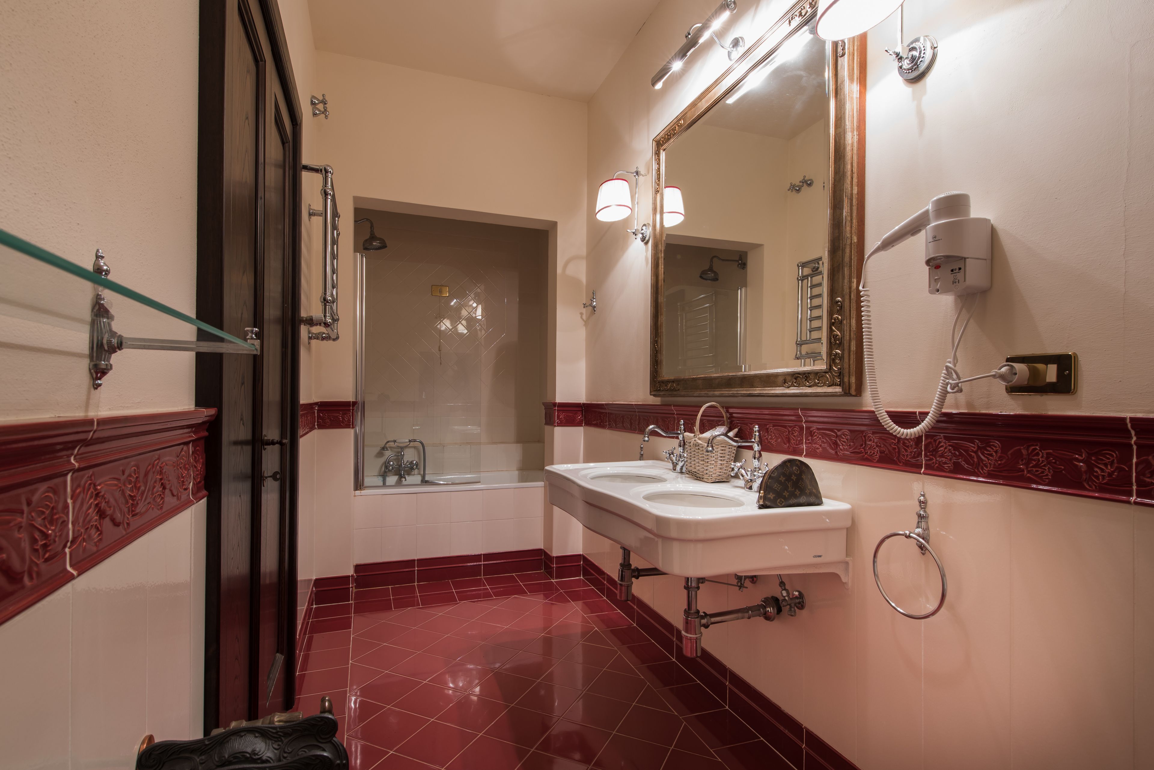 A bathroom with a glass shower enclosure, a vanity with a mirror, and a hairdryer mounted on the wall.