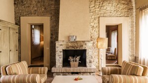 A cozy living room with a stone fireplace, striped sofas, and a coffee table. - Borgo di Pietrafitta Relais (Castellina in Chianti)