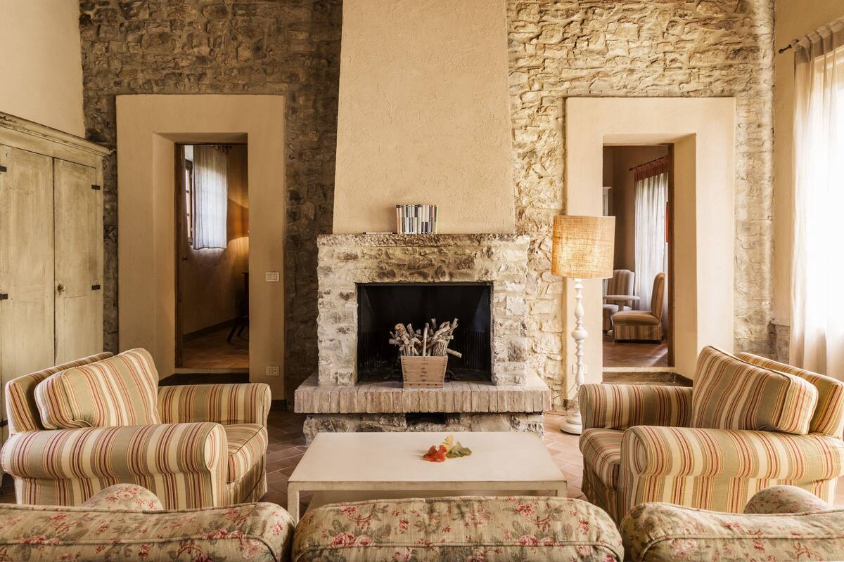 A cozy living room with a stone fireplace, striped sofas, and a coffee table.