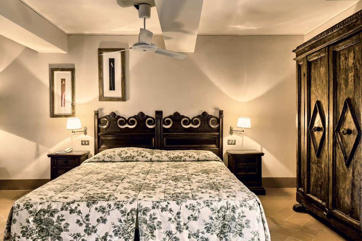 A bedroom with a large bed, two bedside tables, a ceiling fan, and a wooden wardrobe.
