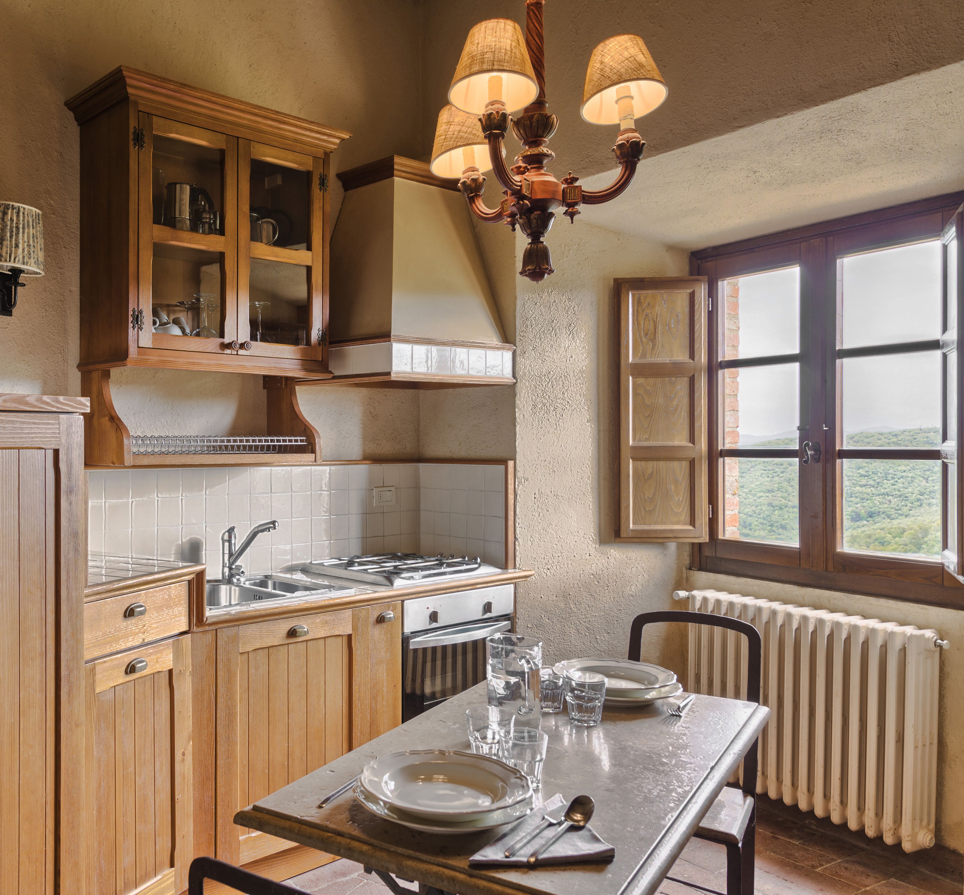 A kitchen with wooden cabinets, a stove, and a dining table set for four.