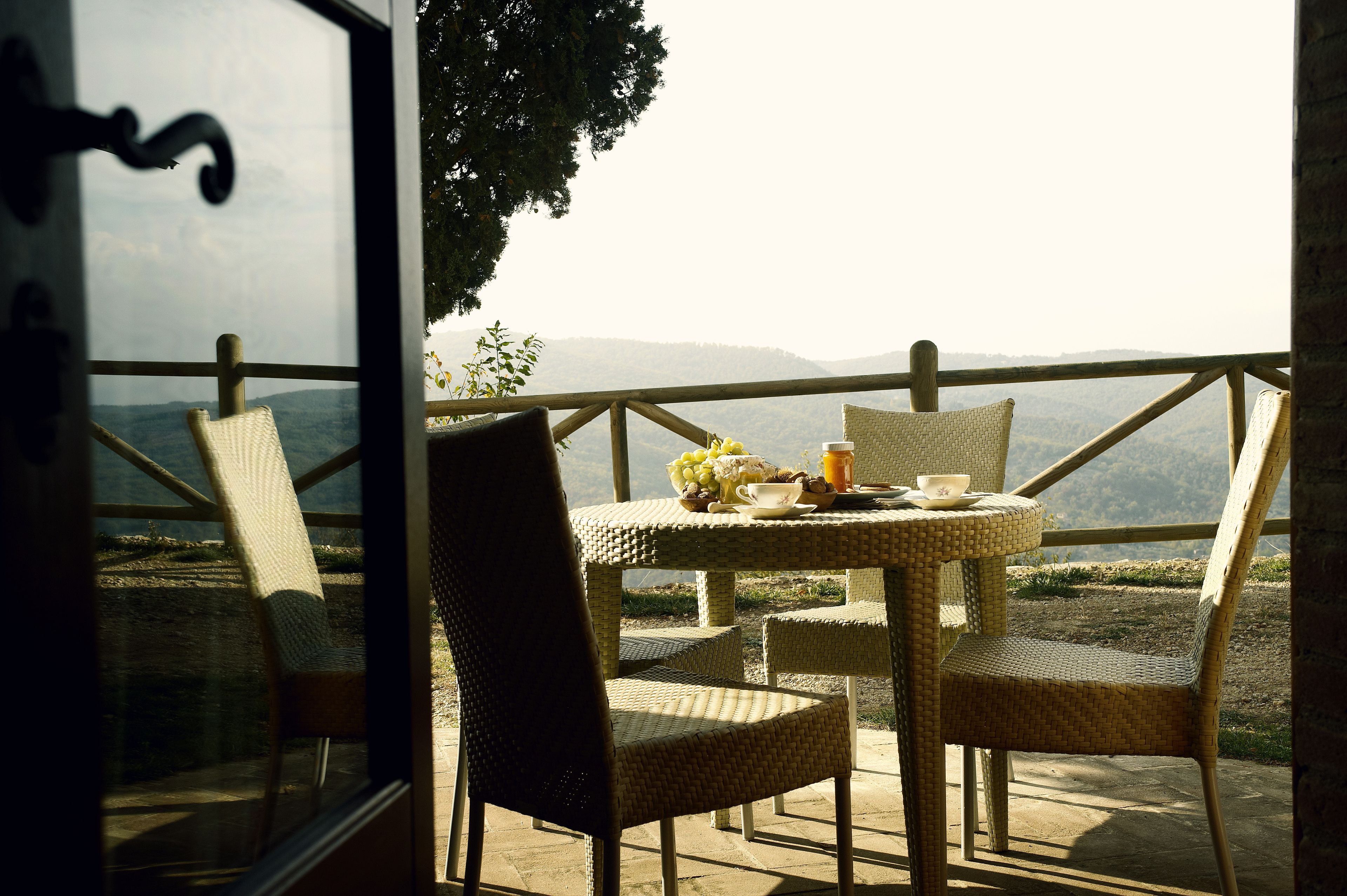 A wicker table with chairs and a view of a mountainous landscape.