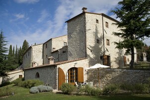 Un edificio in pietra con un cortile, una zona salotto coperta e un campanile.