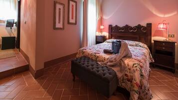 Un dormitorio con cama, mesita de noche, lámpara, banco y una puerta.