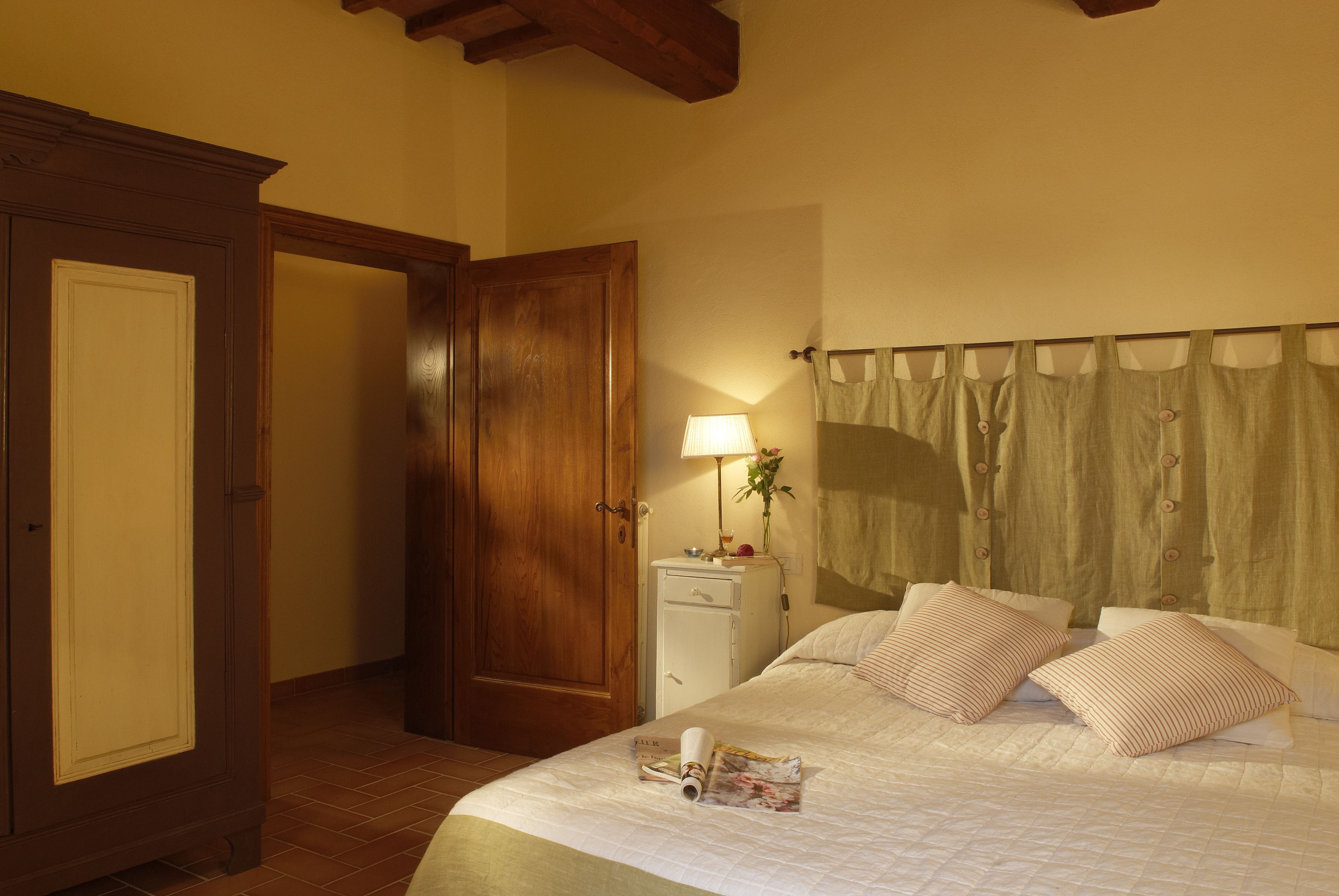 A bedroom with a bed, a nightstand, a lamp, and a door.