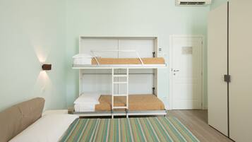 Una camera con un letto a castello, una scala, una porta e un condizionatore.