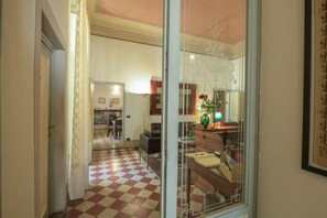 A hallway with a checkered floor leading to a dining area with chairs and a table. - Casa Rovai Guest House (Florence)