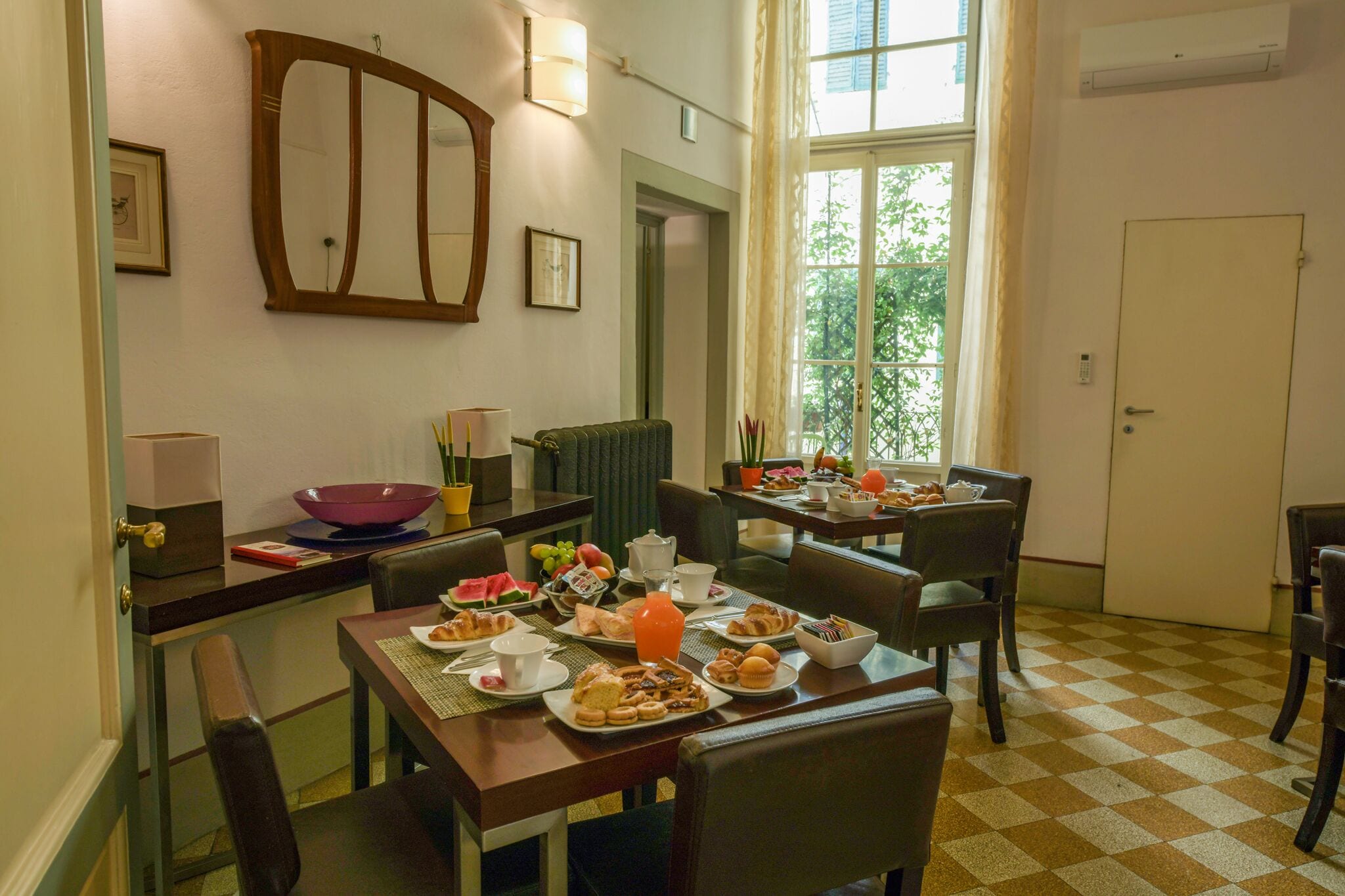 Un comedor con piso a cuadros, un ventanal con vistas y una mesa dispuesta para el desayuno.