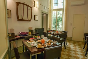 A dining area with a checkered floor, a large window with a view, and a table set with breakfast. - Casa Rovai Guest House (Florence)