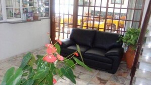 A living room with a black sofa, a patterned rug, and a potted plant. - Pensão Residencial Vila Teresinha (Funchal)
