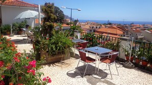A terrace with outdoor seating, potted plants, and a view of the sea. - Pensão Residencial Vila Teresinha (Funchal)