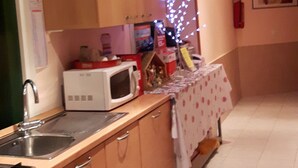 A kitchen with wooden cabinets, a microwave, and a sink. There is a small table with a cloth and a toy house. - Palma Residence (Rome)