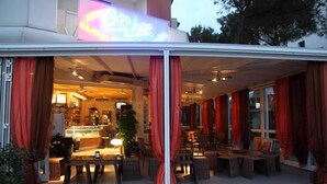 A restaurant with a glass enclosure, red curtains, and indoor seating.