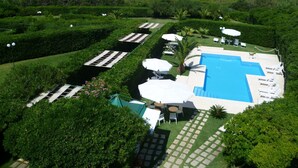 A pool area with a clear view of the sea, surrounded by neatly trimmed hedges and sun loungers. - Resort Puntacassano (Melendugno)
