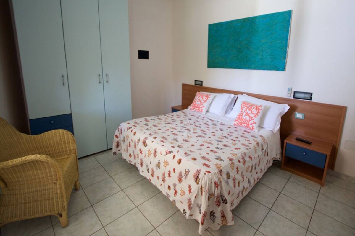 Une chambre à coucher comprenant un lit, une table de chevet, une armoire et une chaise.