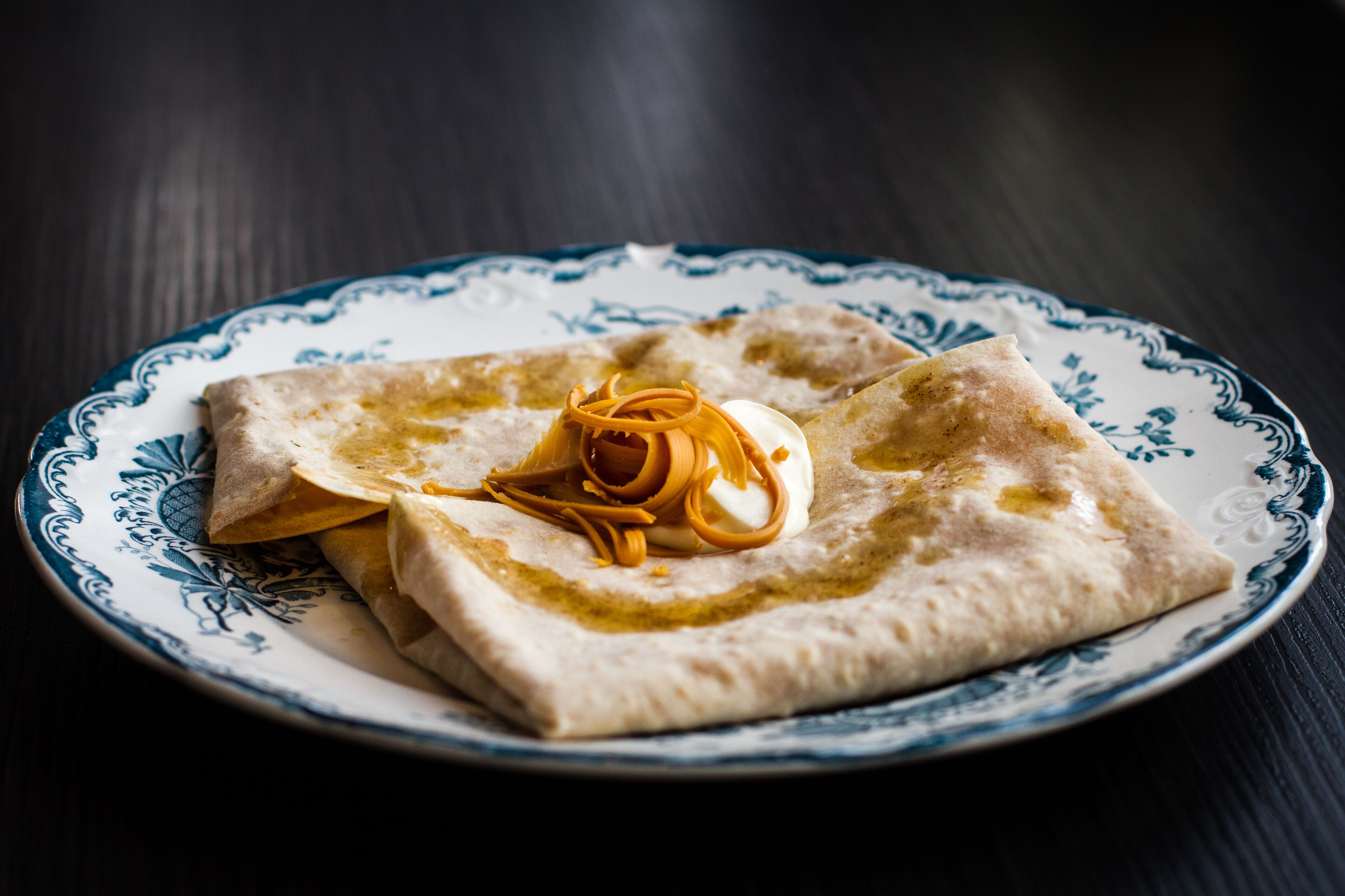 Un plato con un alimento enrollado, posiblemente un pastel, sobre una placa decorativa.