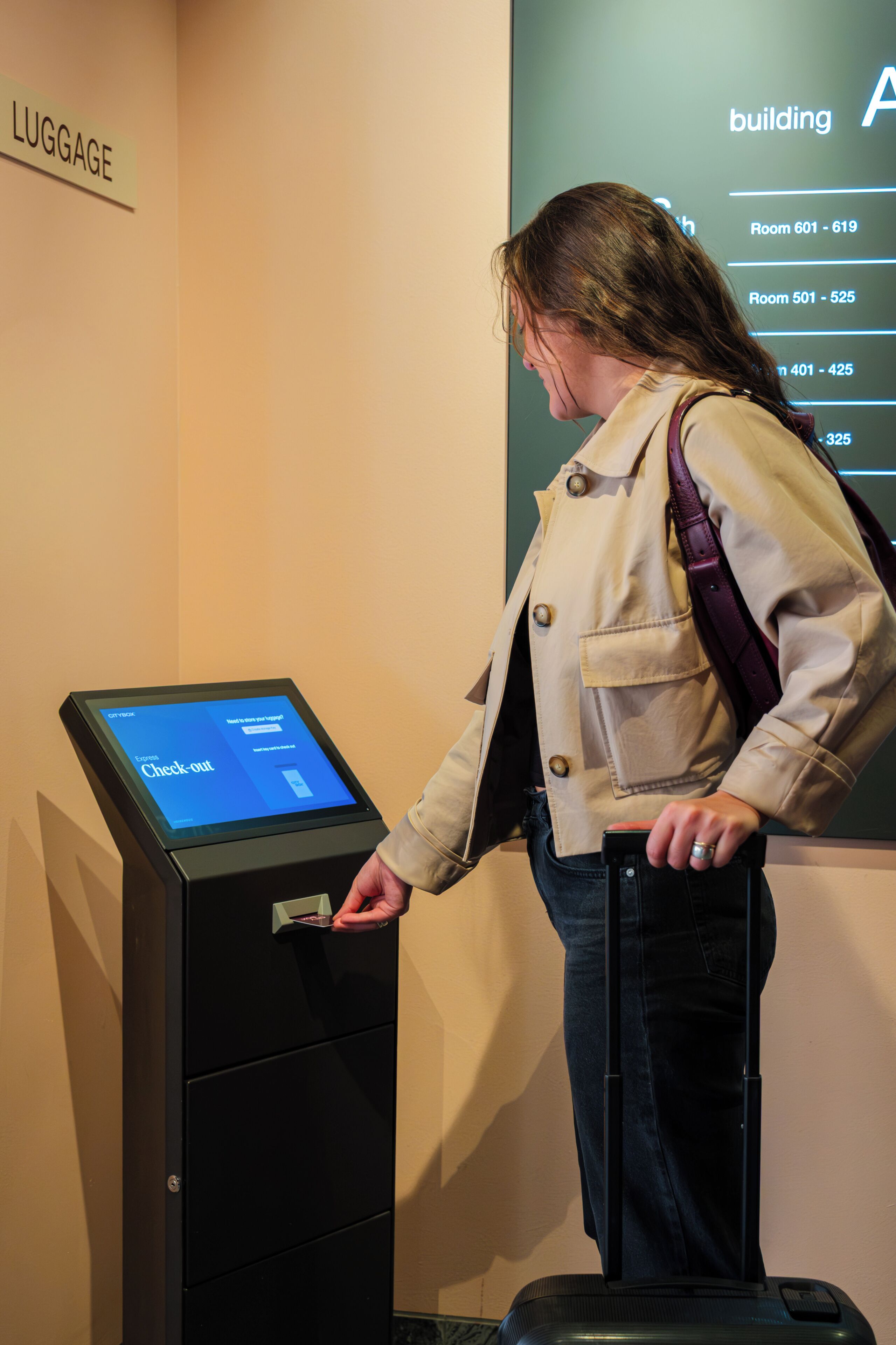Una persona utilizando una máquina de autoservicio para el registro de equipaje en un edificio con la leyenda 'LUGGAGE'.