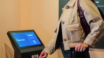 Una persona utilizando una máquina de autoservicio para el registro de equipaje en un edificio con la leyenda 'LUGGAGE'.