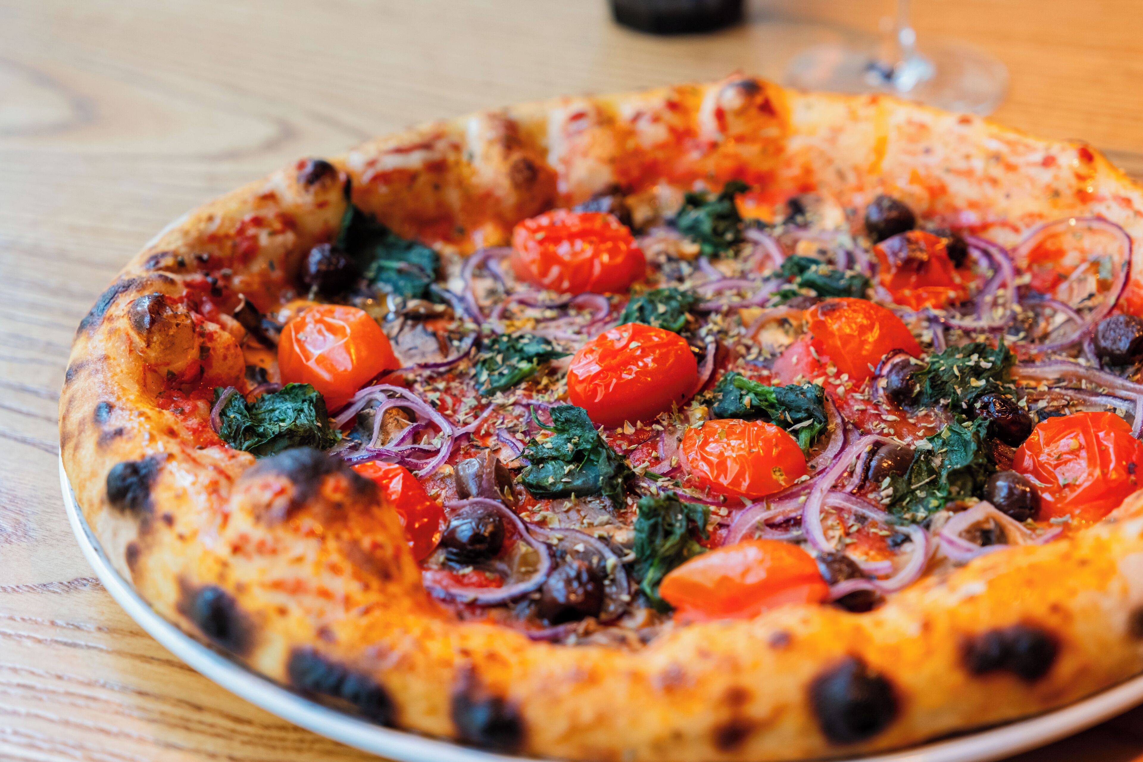A pizza with toppings on a wooden table.