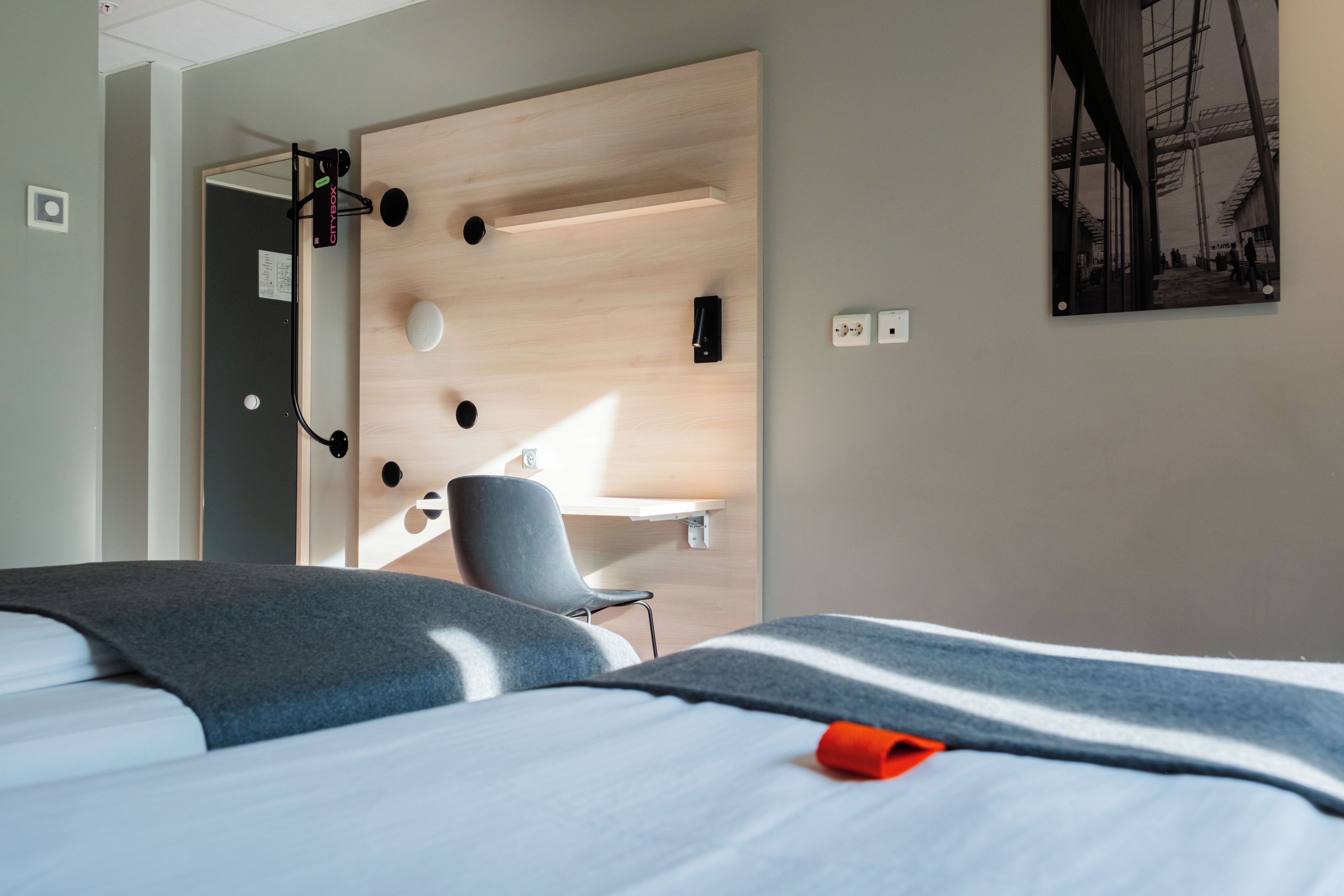A hotel room with a bed, a desk, and a chair.