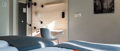 A hotel room with a bed, a desk, and a chair.