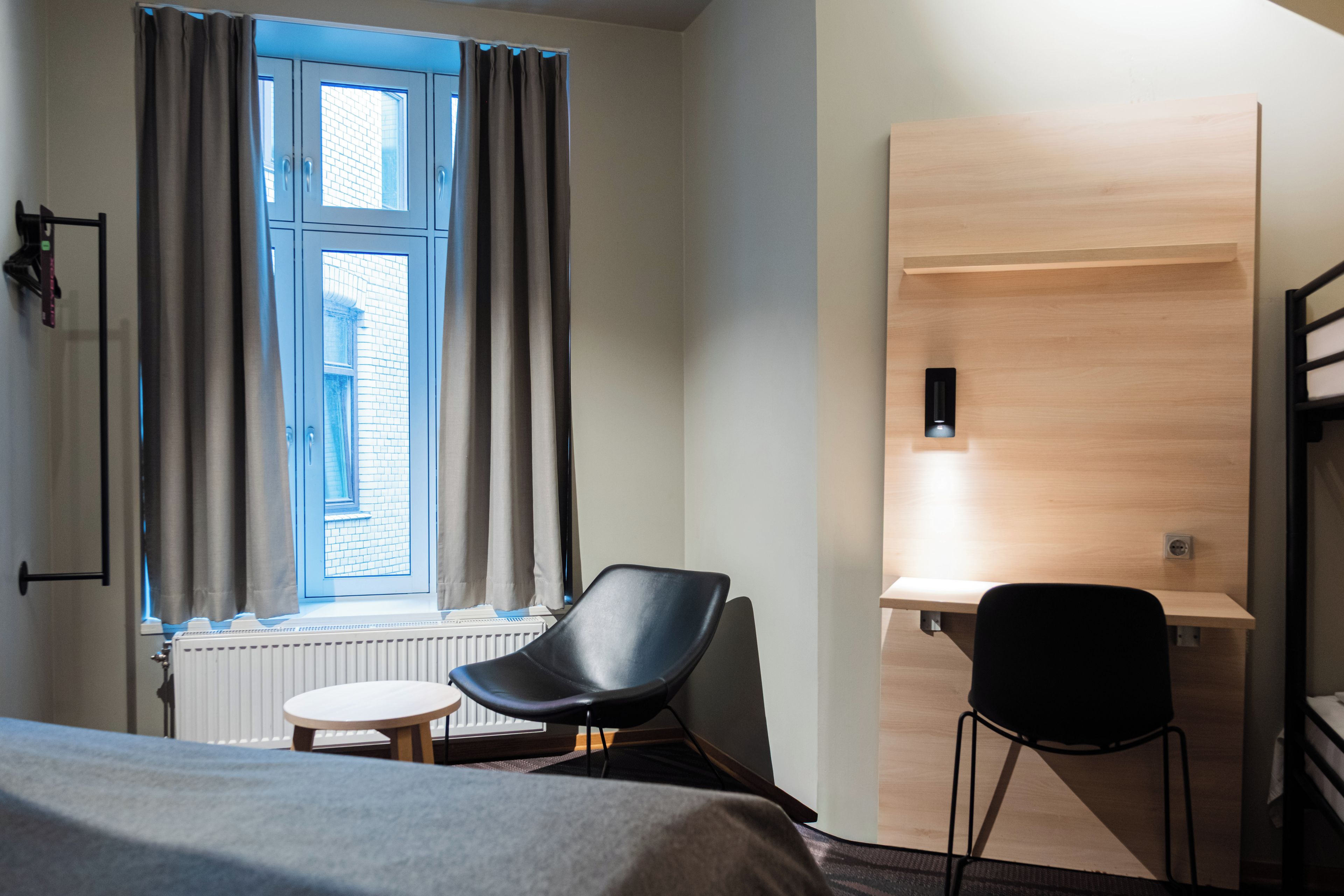 A hotel room with a bed, a desk, and a chair.