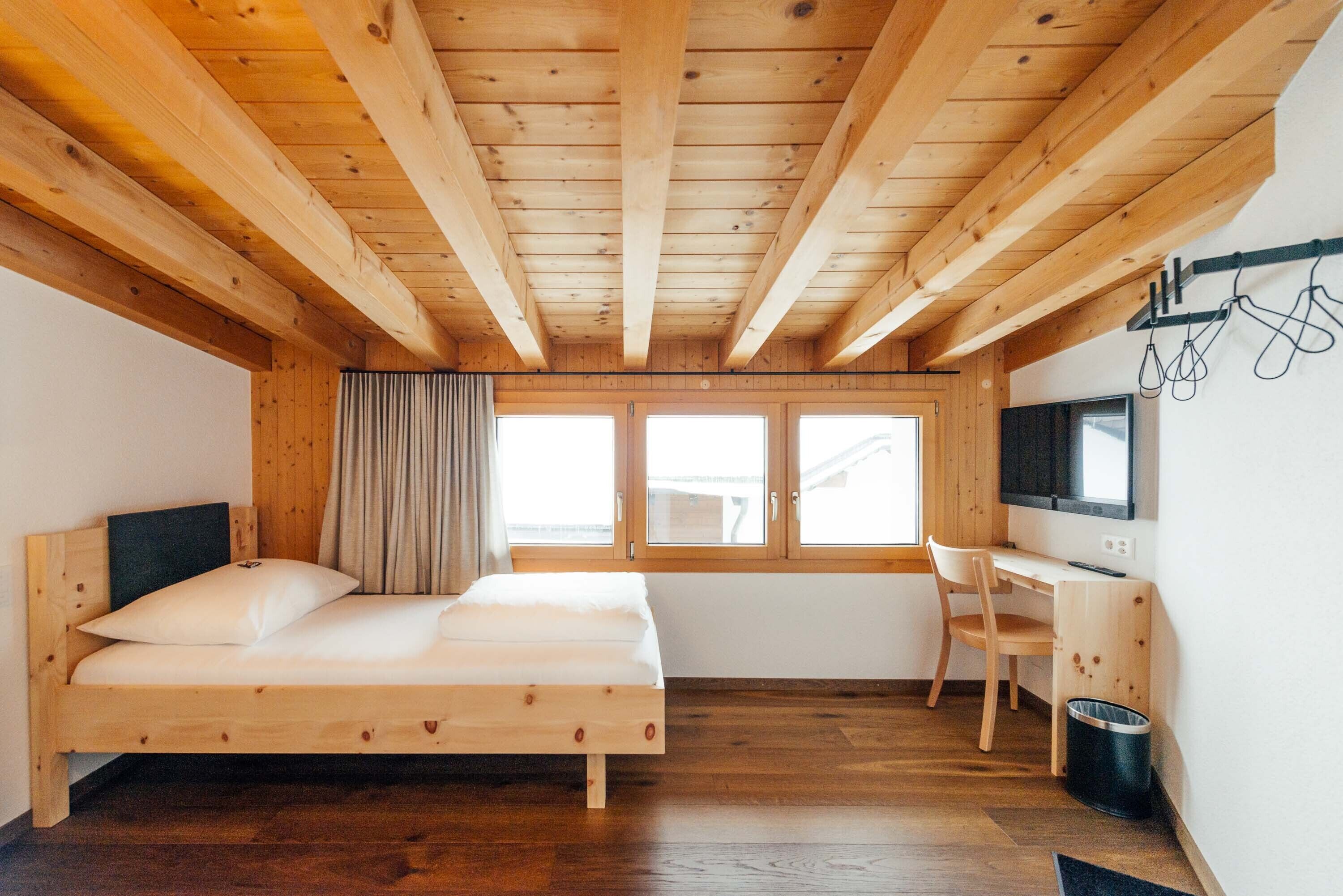 Une pièce en bois avec un lit, un bureau et un téléviseur.