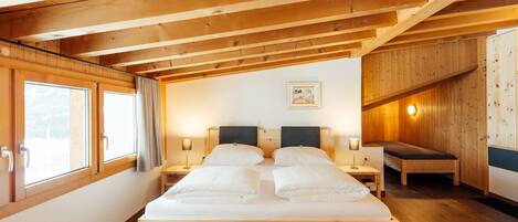A wooden room with a bed, bedside tables, and a bench.
