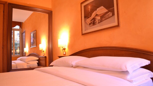A hotel room with a large bed, a wooden headboard, a mirror, and a framed picture on the wall. - Guest House Masterintrastevere (Rome)