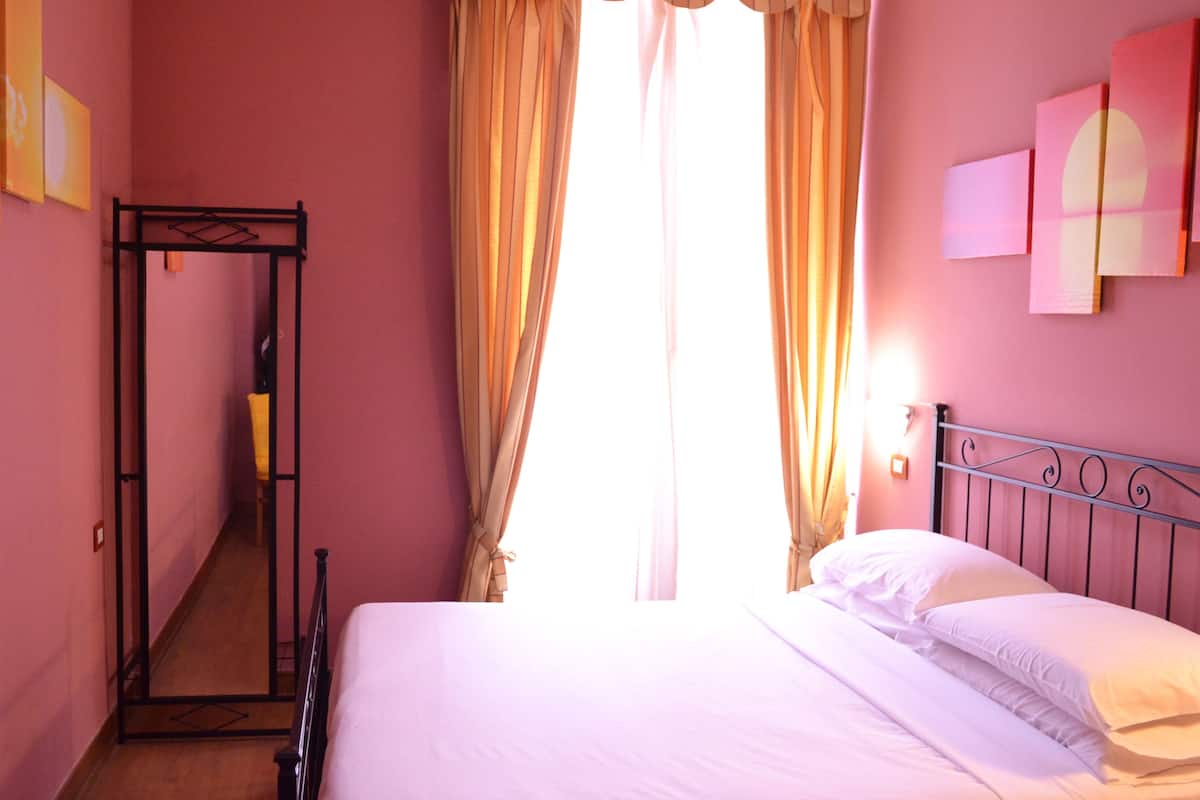 Un dormitorio con cama, armario y ventana con cortinas.