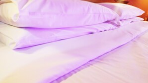 A bed with white and lavender bedding. - Guest House Masterintrastevere (Rome)
