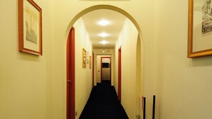 A narrow hallway with a black carpet, wooden doors, and framed pictures on the walls. - Guest House Masterintrastevere (Rome)