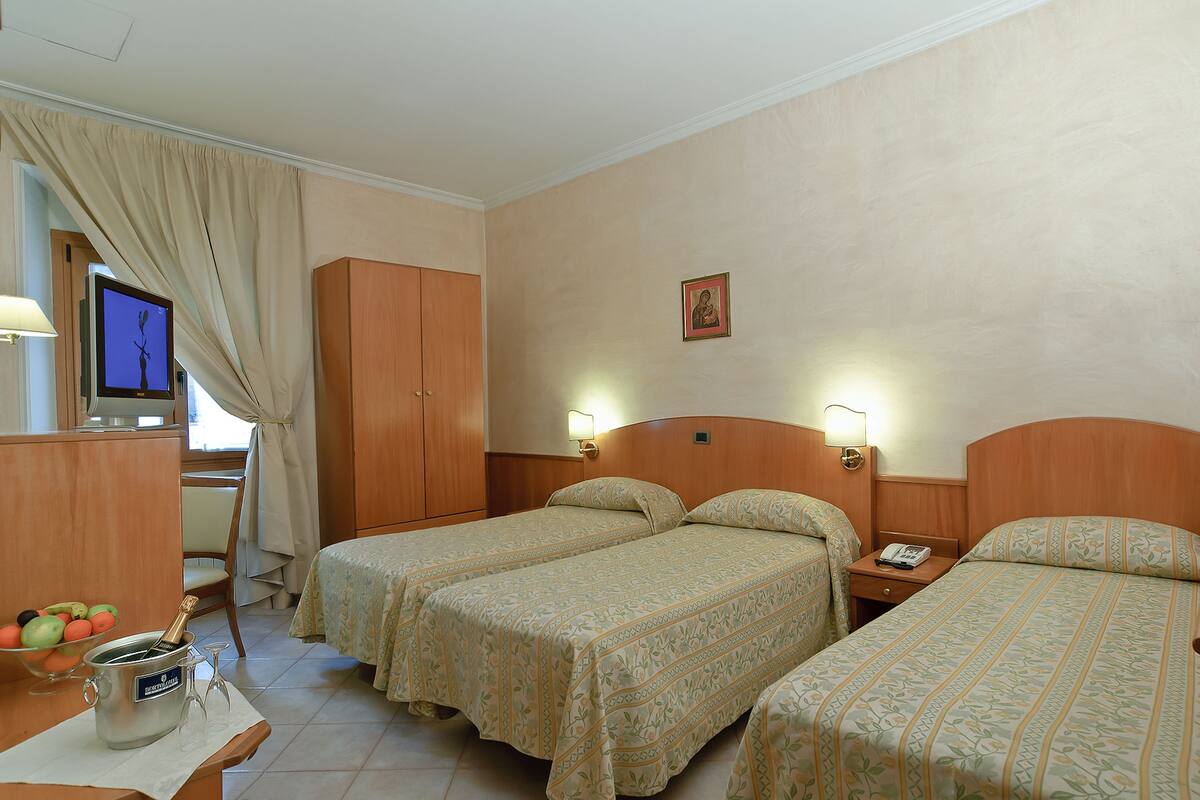 Habitación de hotel con dos camas, un escritorio con computadora, un televisor y un minibar.