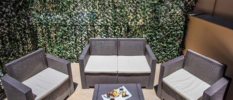 A patio area with wicker furniture and a table set with pastries.