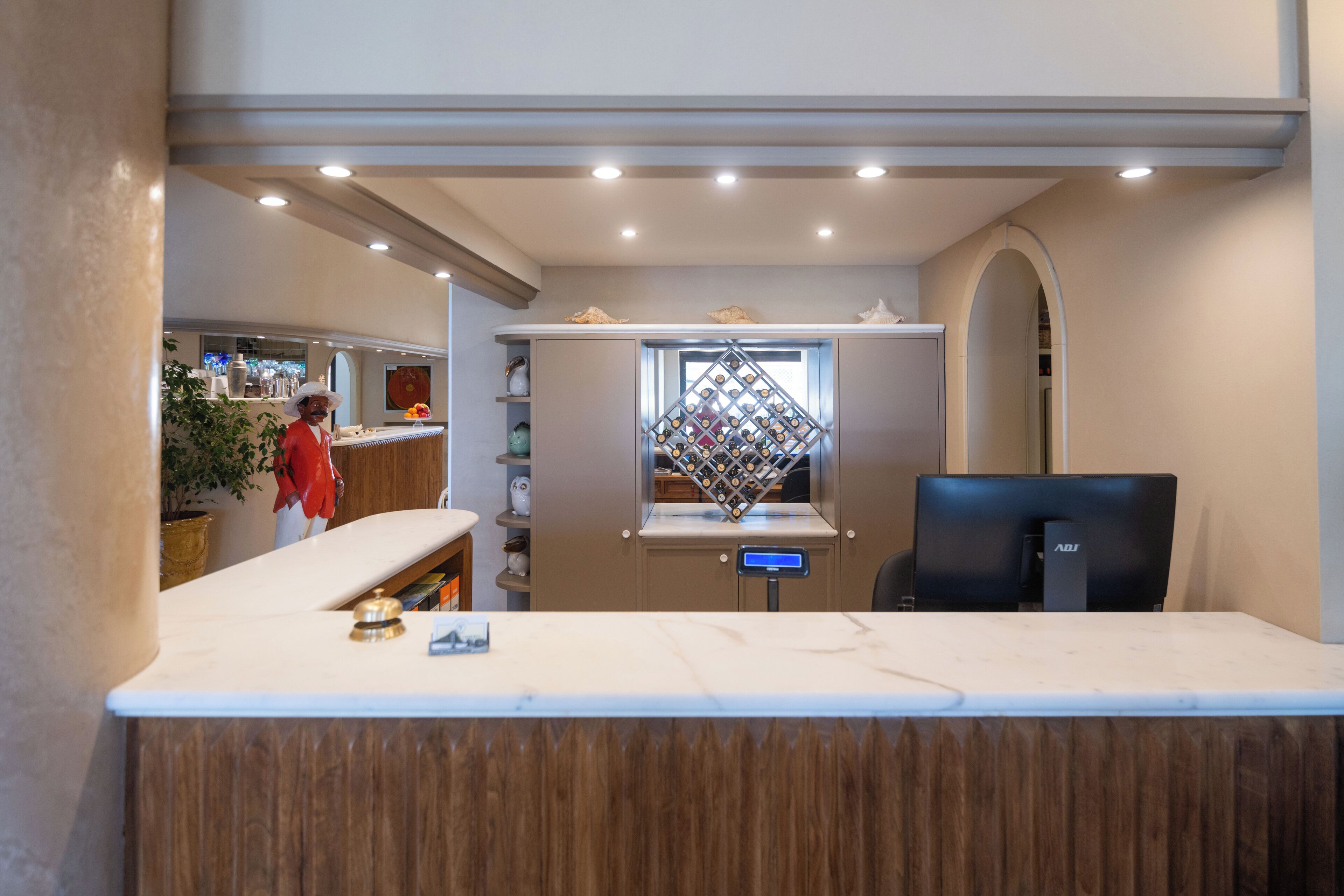 A reception area with a marble counter, a computer, and a wine rack.
