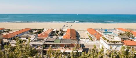 A coastal hotel with multiple buildings, a swimming pool, and a beach view.