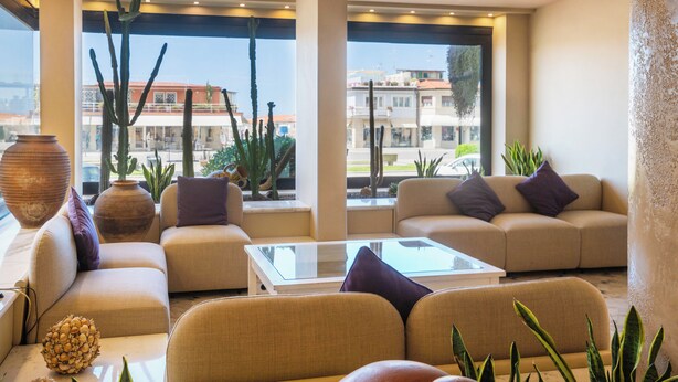 Una sala de estar moderna con sofás, una mesa de centro y grandes ventanales con vistas a la ciudad.